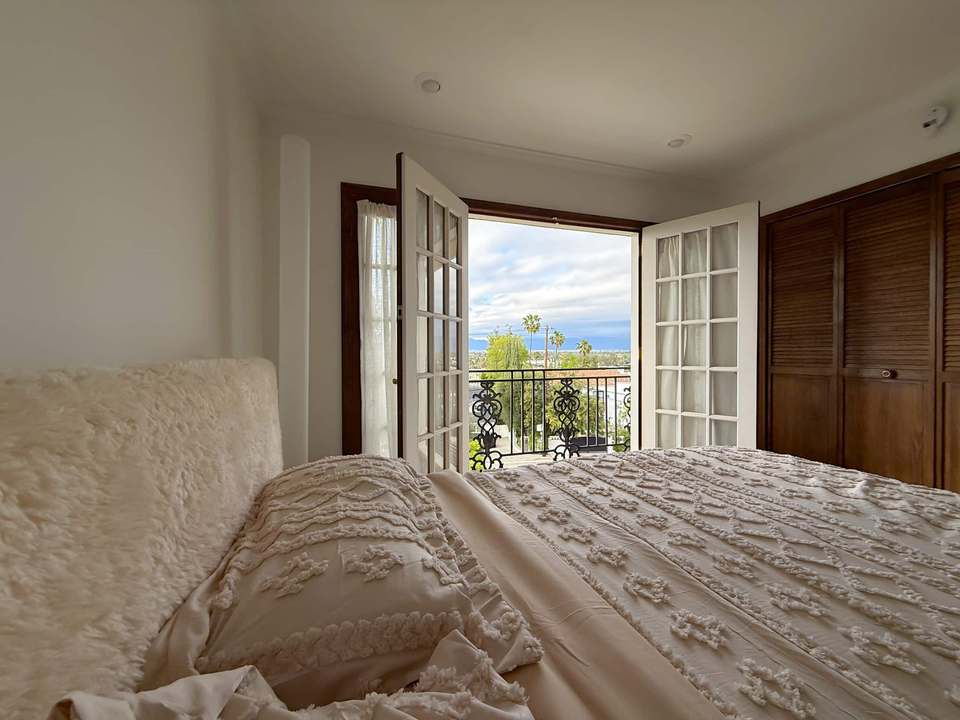 California king bed with textured bedding and French doors open to a balcony