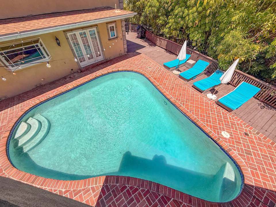 Looking down from the rooftop at the oval pool, brick deck and loungers