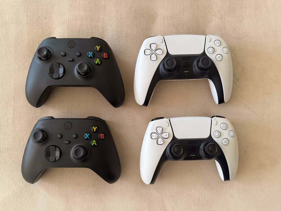 Two Xbox Series X and two PS5 DualSense controllers laid out for game night