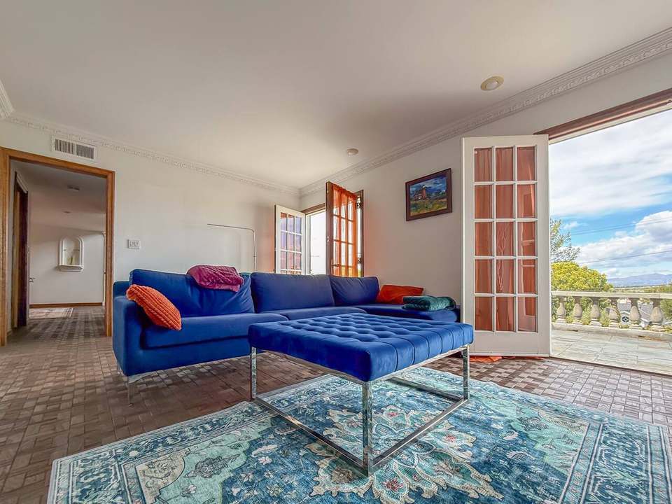 Family room with a blue velvet sectional on patterned tile, French doors open to the terrace