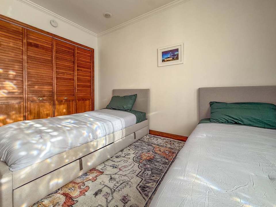Twin bedroom with two single beds with under-bed storage and dappled window light