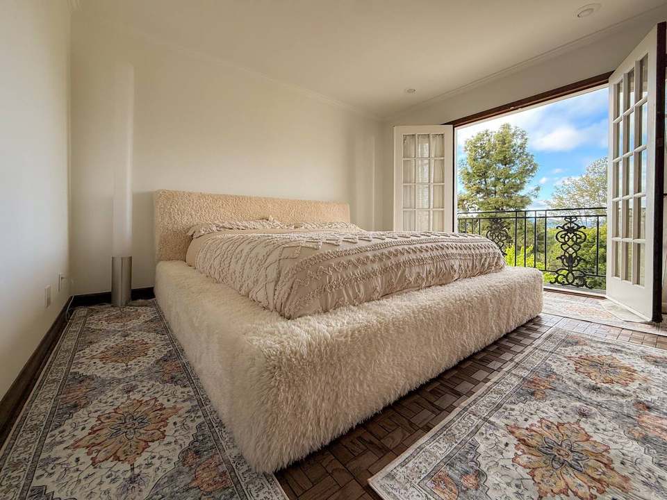 California king bed with a faux-fur frame beside French doors to a Juliet balcony