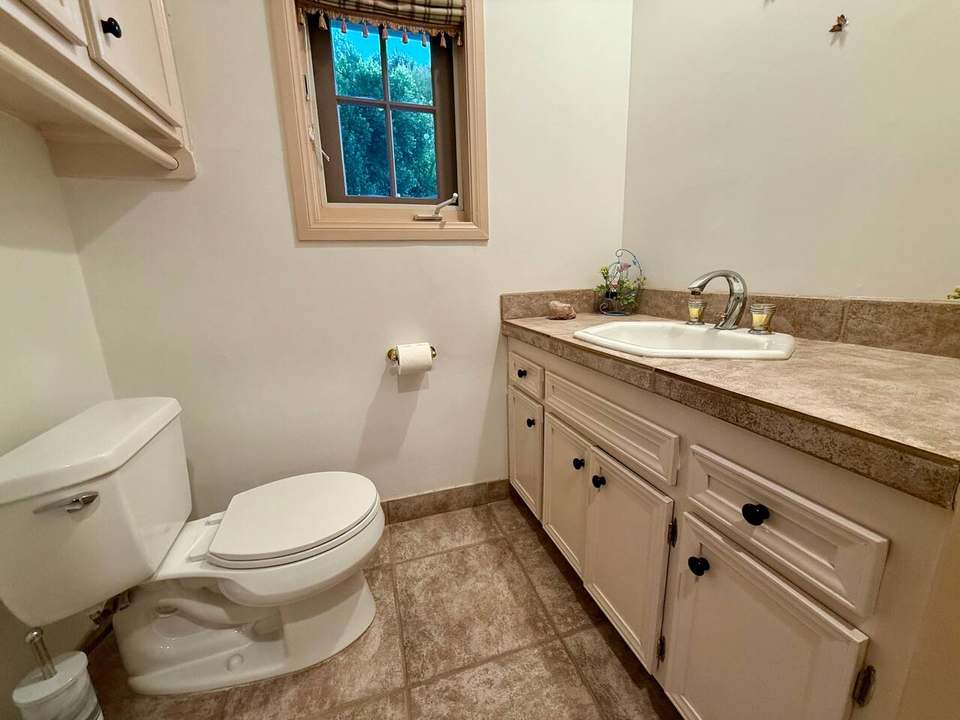 Downstairs half bath with a stone-tile floor and a wood vanity