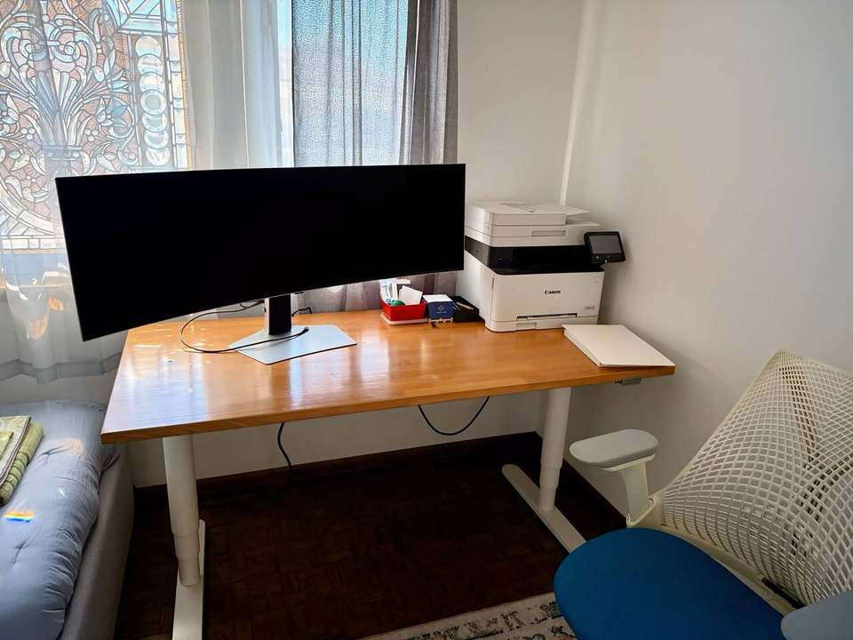 Electric sit/stand desk with a 49-inch ultra-wide monitor, printer and ergonomic chair