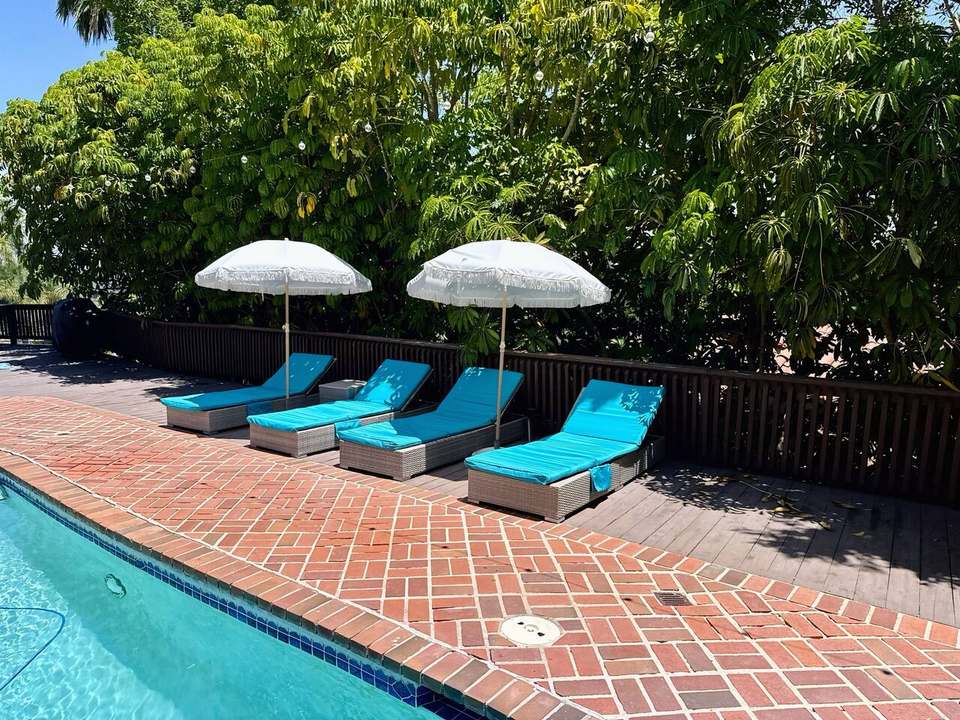 Four turquoise loungers under white umbrellas on the brick pool deck