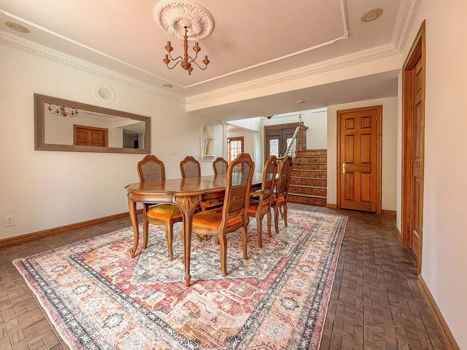 Dining room with a carved oval table, cane-back chairs and a patterned rug